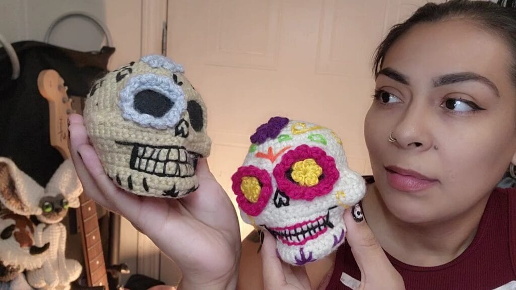 Calaveras a Crochet decoradas como calaveras de azucar, sostenidas en manos